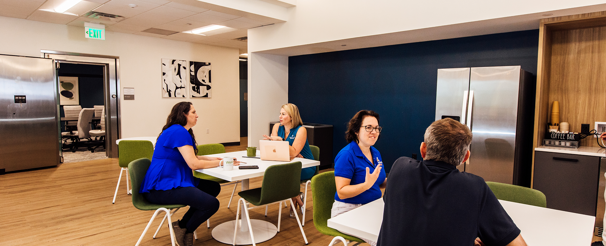 Professionals sitting and talking around tables in a coworking area