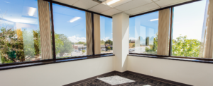 A corner office space with windows looking out on trees on a sunny day